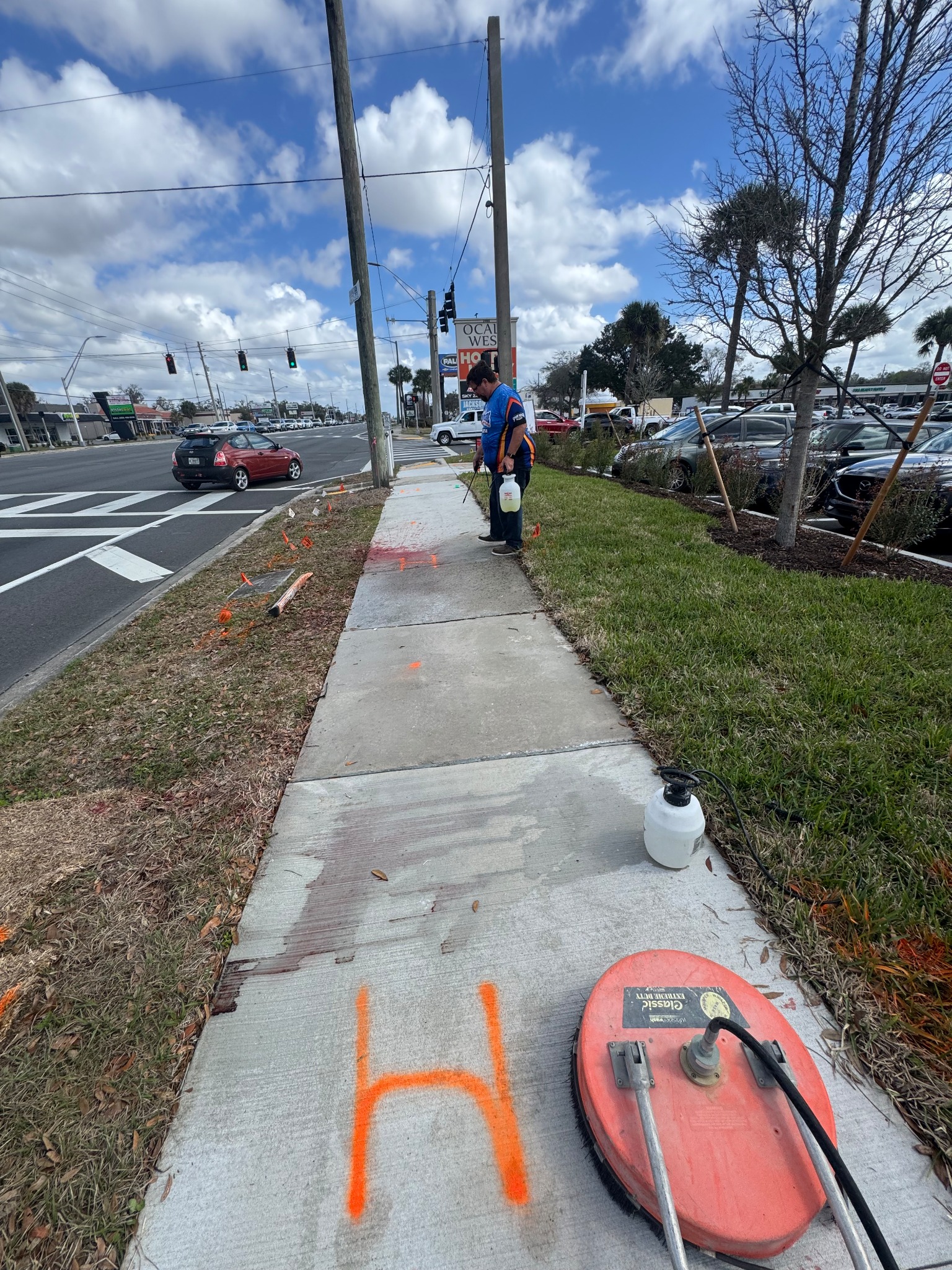 A surface cleaner on the sidewalk while a UPPW worker treats remaining red dye farther along the concrete.