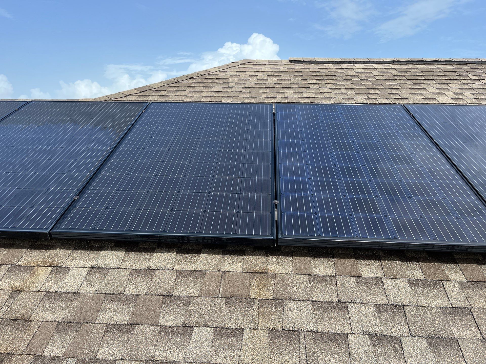 Close view of solar-panel glass and frames on a shingle roof