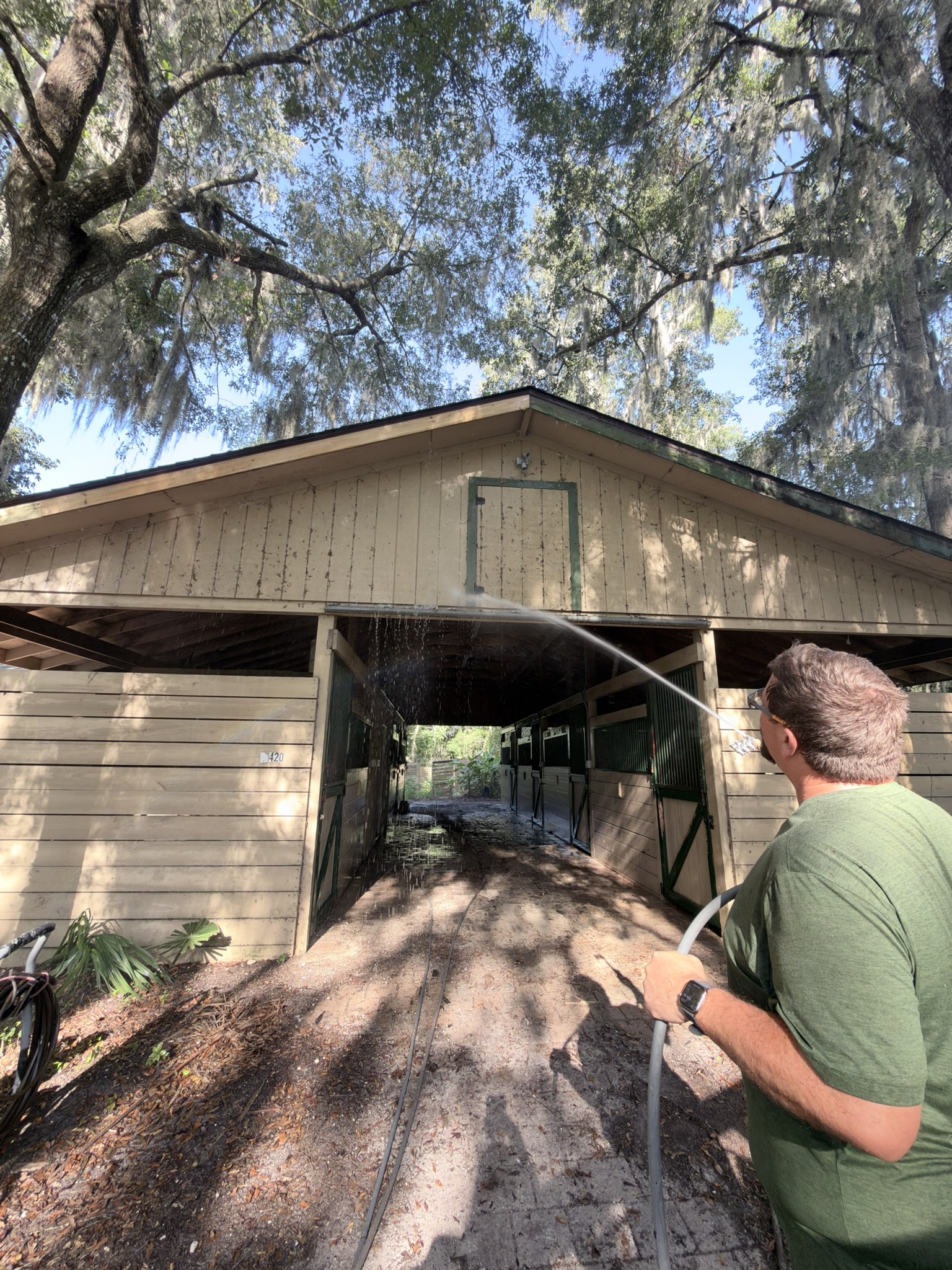 Under Pressure technician washing the front exterior of a horse barn